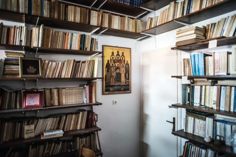 Εσωτερικό δωματίου με ξύλινα ράφια γεμάτα βιβλία και μια θρησκευτική εικόνα στον τοίχο.