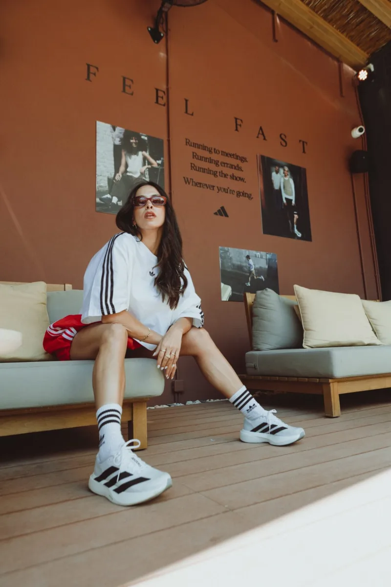 Γυναίκα με αθλητικά ρούχα adidas κάθεται σε καναπέ.
