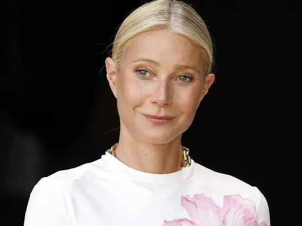 Η Gwyneth Paltrow ποζάρει χαμογελαστή σε επίσημη εμφάνιση, εκπροσωπώντας τον υγιεινό τρόπο ζωής και την ευεξία.