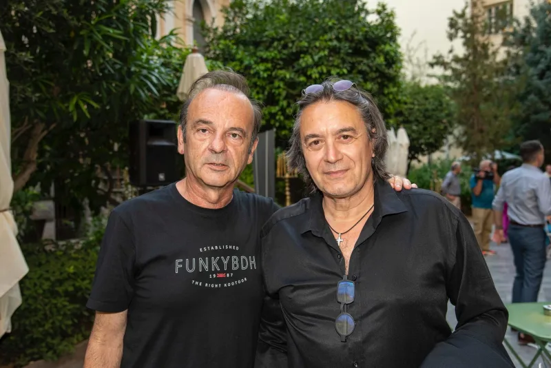 Ο Σταύρος Ξαρχάκος με έναν άνδρα σε εξωτερικό χώρο.