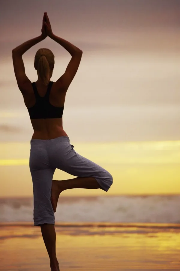 Γυναίκα εκτελεί τη στάση του δέντρου στη yoga για ενδυνάμωση γλουτών και συγκέντρωση.