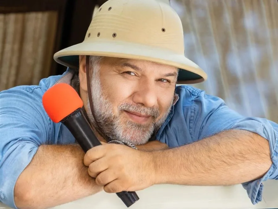 Ο Γρηγόρης Αρναούτογλου με καπέλο σαφάρι και μικρόφωνο.