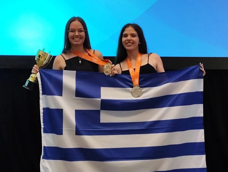 Η Ελένη Καρακασίδου και η Κυριακή Πέτσα κρατούν την ελληνική σημαία, ένα κύπελλο και τα μετάλλιά τους.