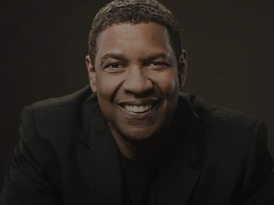 Ο Denzel Washington χαμογελάει φορώντας μαύρο σακάκι.