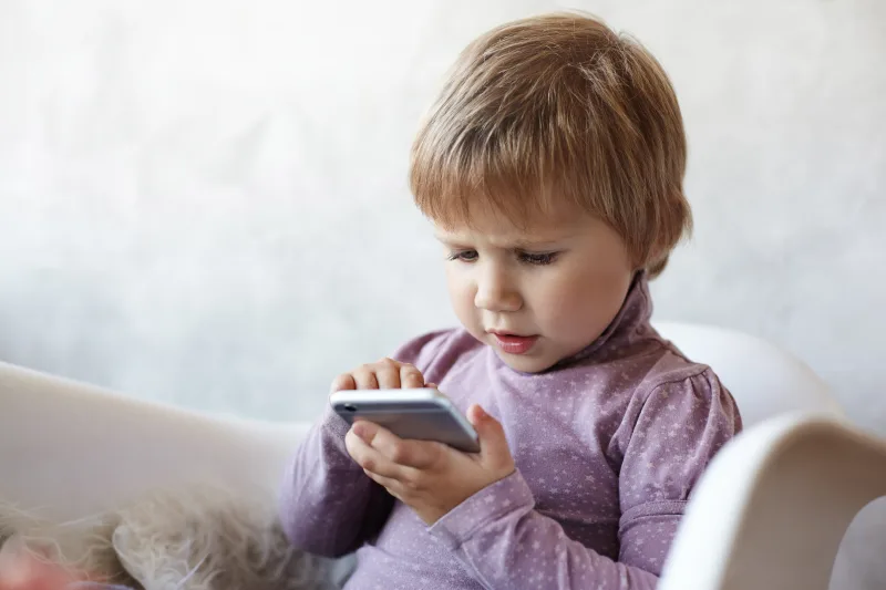 Παιδί που χρησιμοποιεί tablet ή smartphone, εστιάζοντας στην επίδραση της οθόνης στον παιδικό εγκέφαλο.