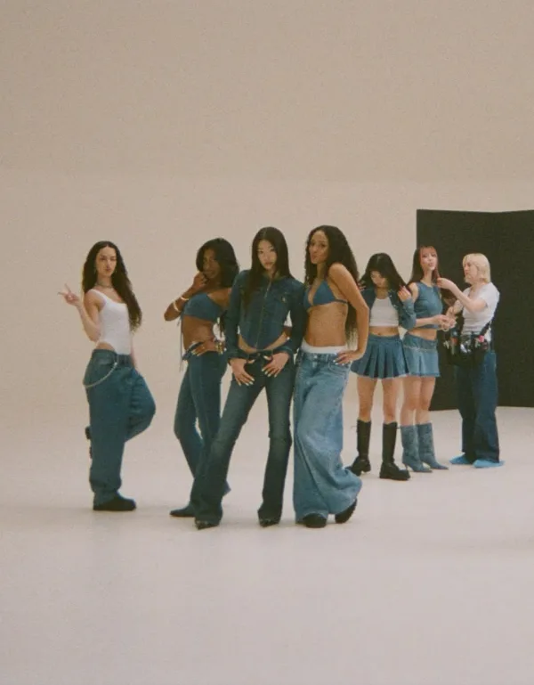 Το συγκρότημα KATSEYE ποζάρει με denim σύνολα σε λευκό φόντο.