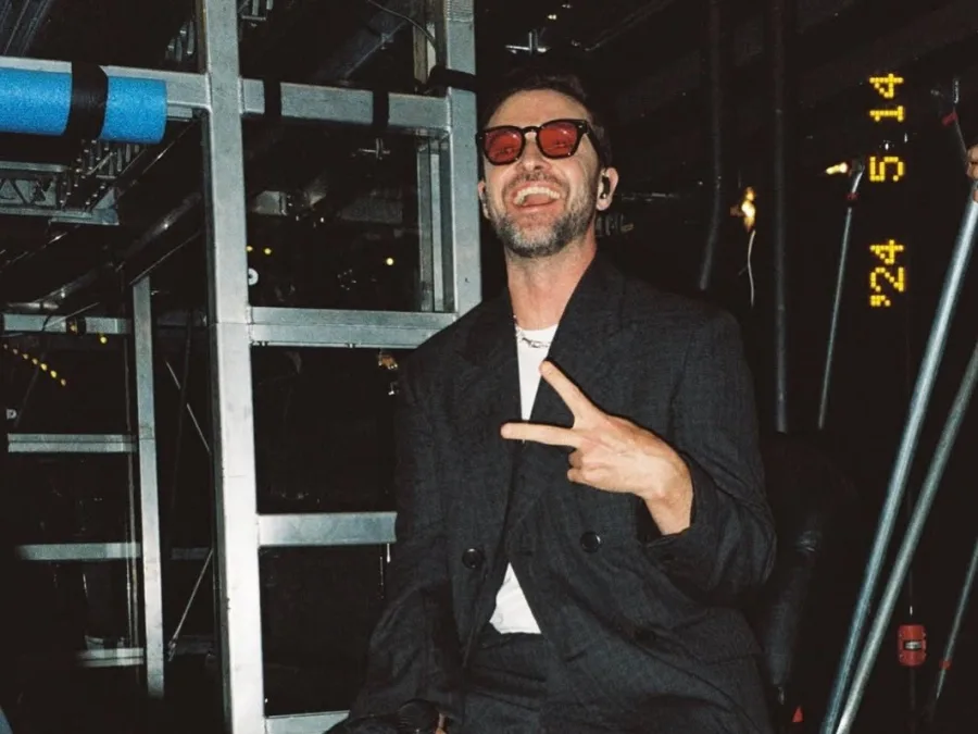Ο Justin Timberlake με γυαλιά ηλίου και μαύρο σακάκι κάνει το σήμα της νίκης.