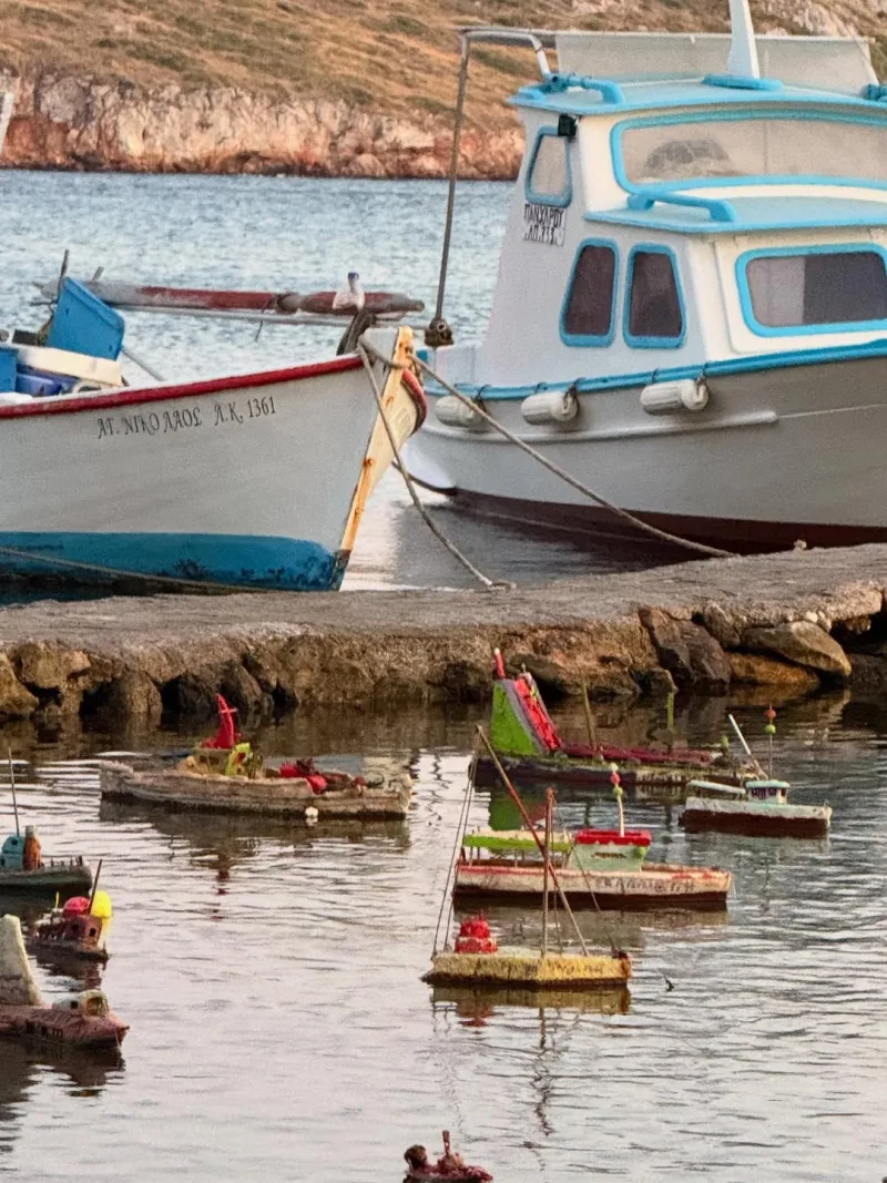 Παραδοσιακές βάρκες και μικρογραφίες πλοίων σε λιμανάκι.