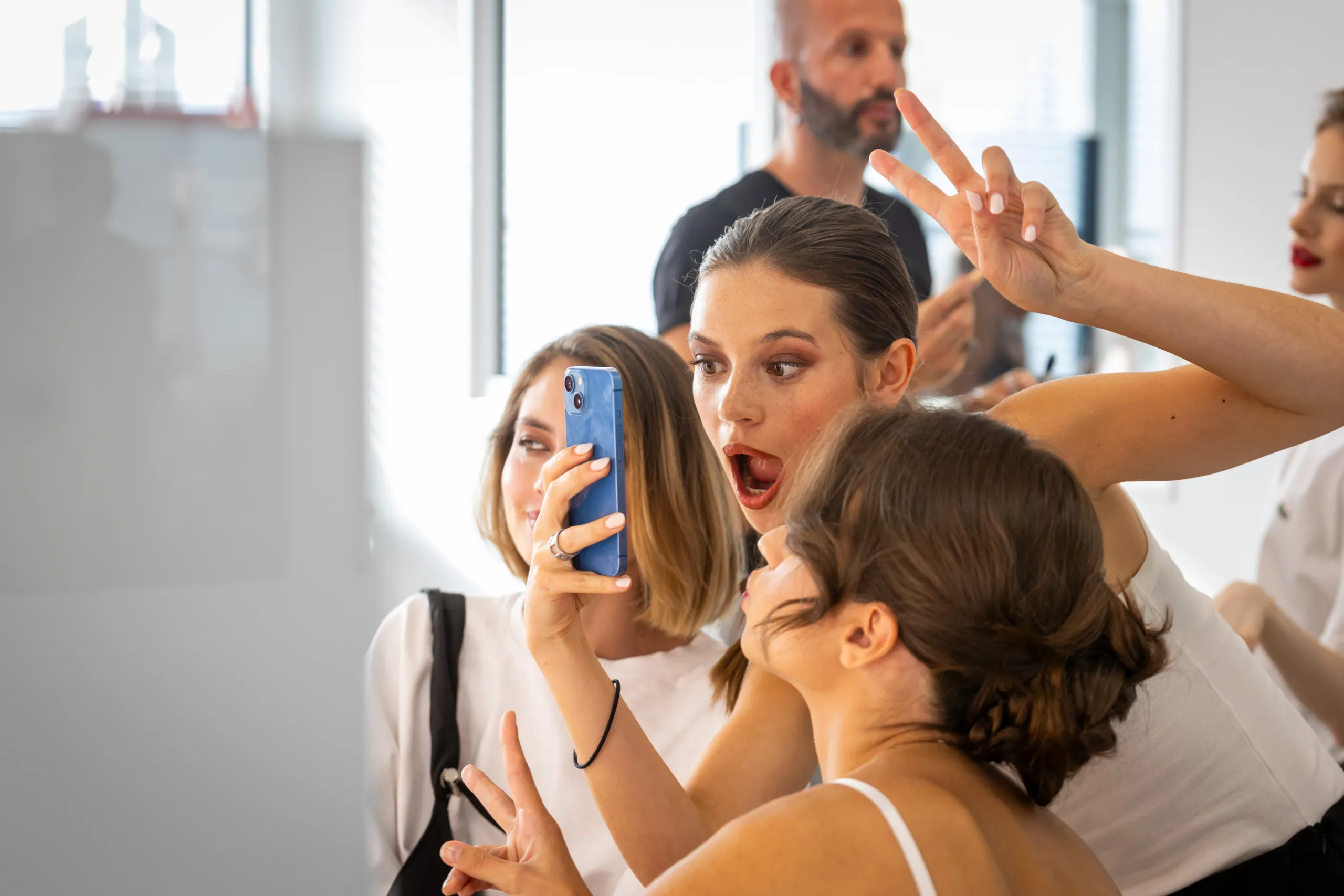 Τρεις νεαρές γυναίκες βγάζουν selfie με smartphone σε εκπαιδευτικό χώρο.