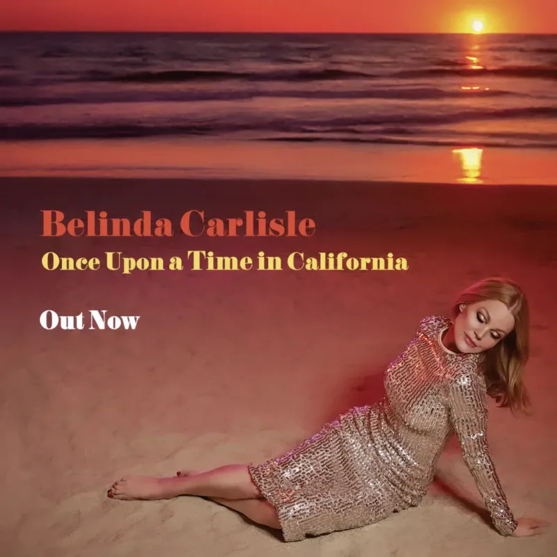 Η Belinda Carlisle ξαπλωμένη στην άμμο κατά τη διάρκεια του ηλιοβασιλέματος.