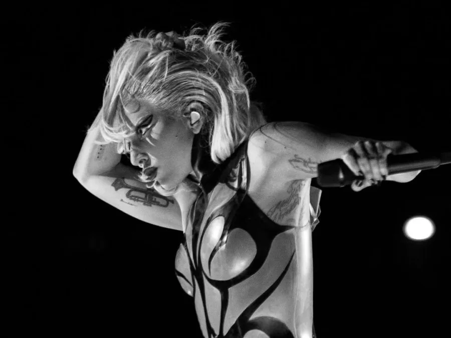 Η Lady Gaga σε ασπρόμαυρη λήψη πάνω στη σκηνή κρατώντας μικρόφωνο.