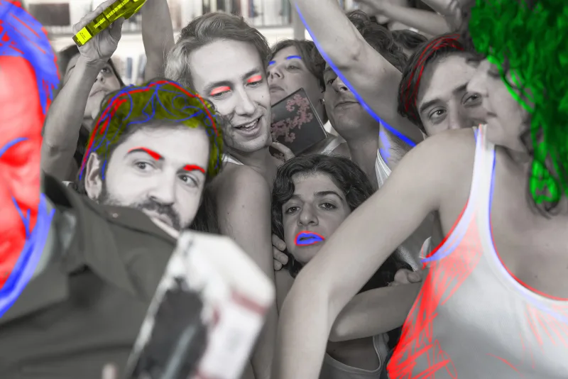 Ομάδα ηθοποιών σε θεατρική παράσταση με έντονα χρώματα και μακιγιάζ.