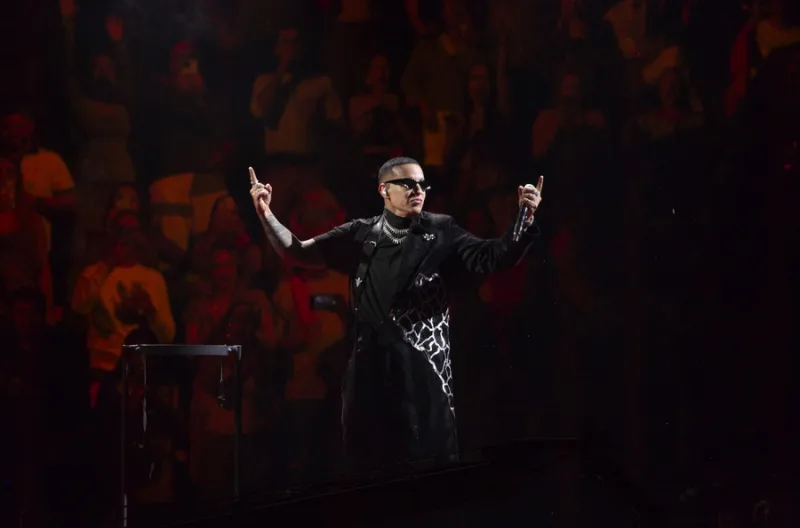 Ο Bad Bunny με τα χέρια υψωμένα στη σκηνή, παρουσιάζοντας ένα από τα κορυφαία latin hits του 21ου αιώνα.
