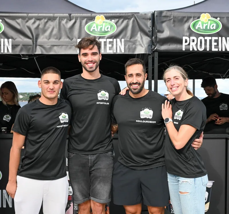 Τέσσερα άτομα με μαύρα μπλουζάκια Arla Protein στο Spetses Mini Marathon 2025.
