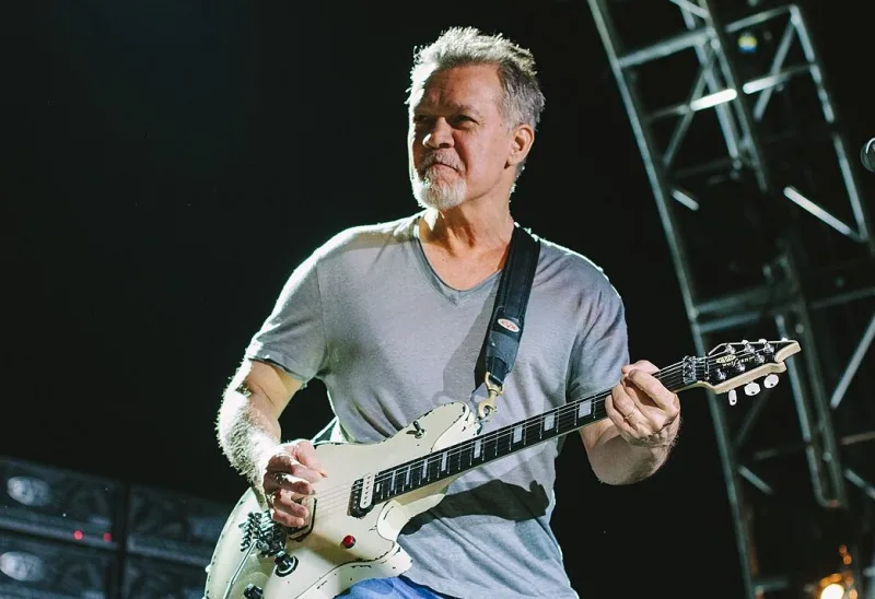 Ο Eddie Van Halen παίζει μια λευκή ηλεκτρική κιθάρα σε συναυλία.