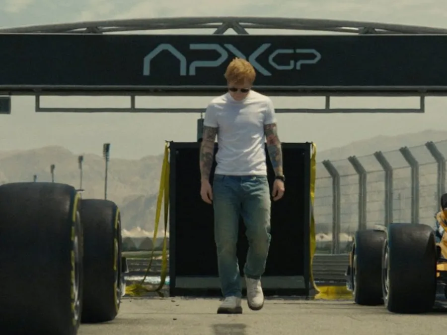 Ο Ed Sheeran περπατά σε πίστα αγώνων F1 κάτω από την επιγραφή APXGP.