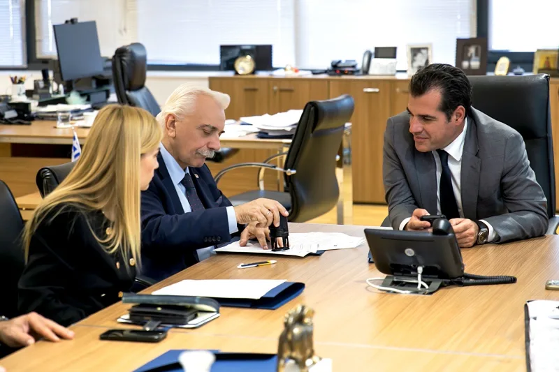 Τρία άτομα σε γραφείο κατά την υπογραφή και σφράγιση εγγράφων.