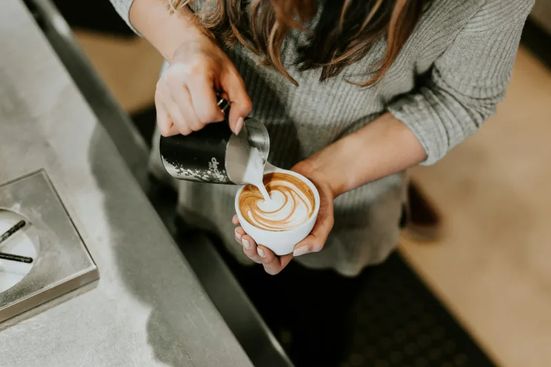 Barista φτιάχνει latte art σε φλιτζάνι καφέ