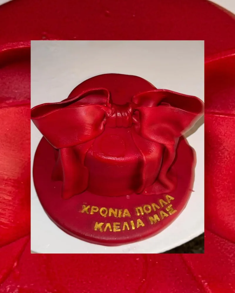 Κόκκινη τούρτα γενεθλίων με μεγάλο φιόγκο και ευχή για την Κλέλια Ανδριολάτου.