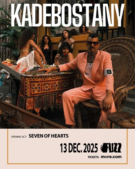 Ο Kadebostany με σομόν κοστούμι και γυαλιά ηλίου κάθεται σε θρόνο από μπαμπού.