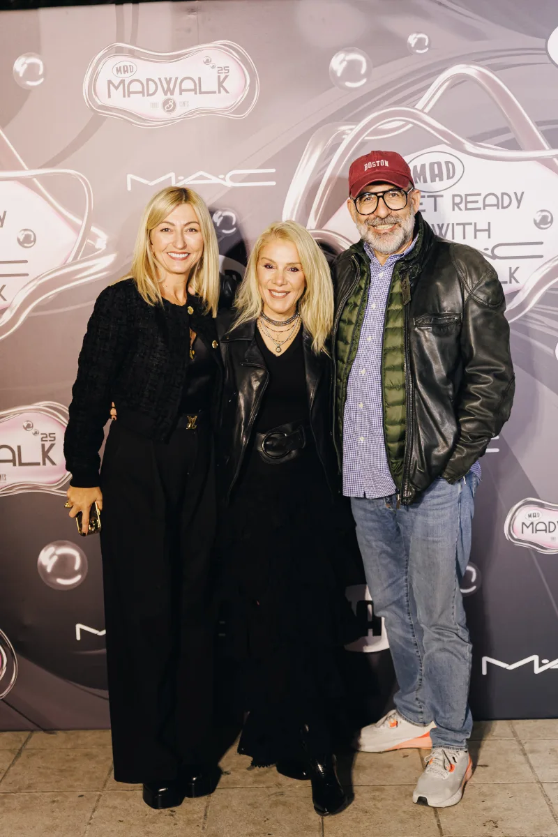 Τρία άτομα ποζάρουν μπροστά από φόντο MadWalk και MAC Cosmetics.