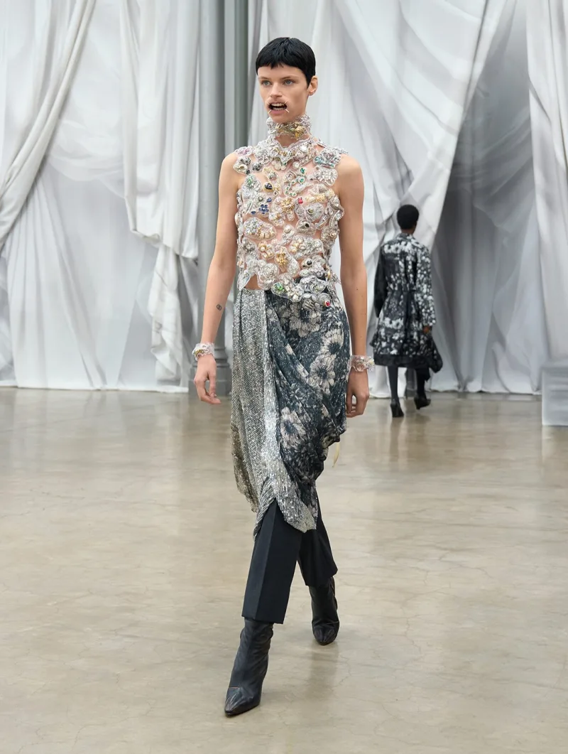 Μοντέλο στην επίδειξη Maison Margiela SS26 με διαφανές τοπ και φλοράλ φούστα.