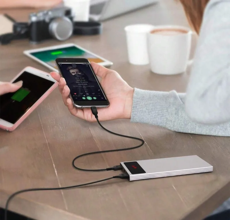 Power bank φορτίζει κινητά τηλέφωνα πάνω σε ξύλινο τραπέζι.