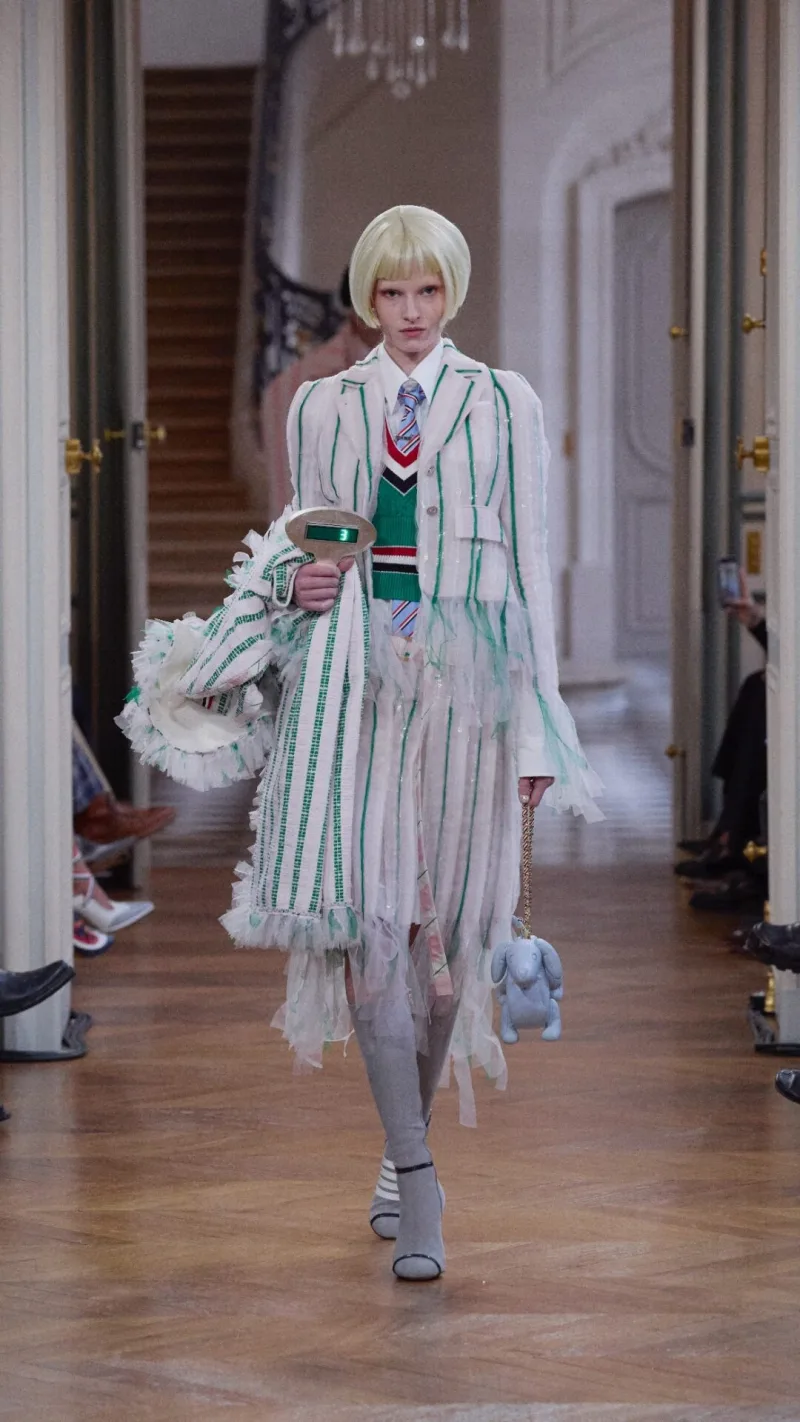 Μοντέλο στην επίδειξη Thom Browne SS26 με ριγέ κοστούμι και αξεσουάρ.