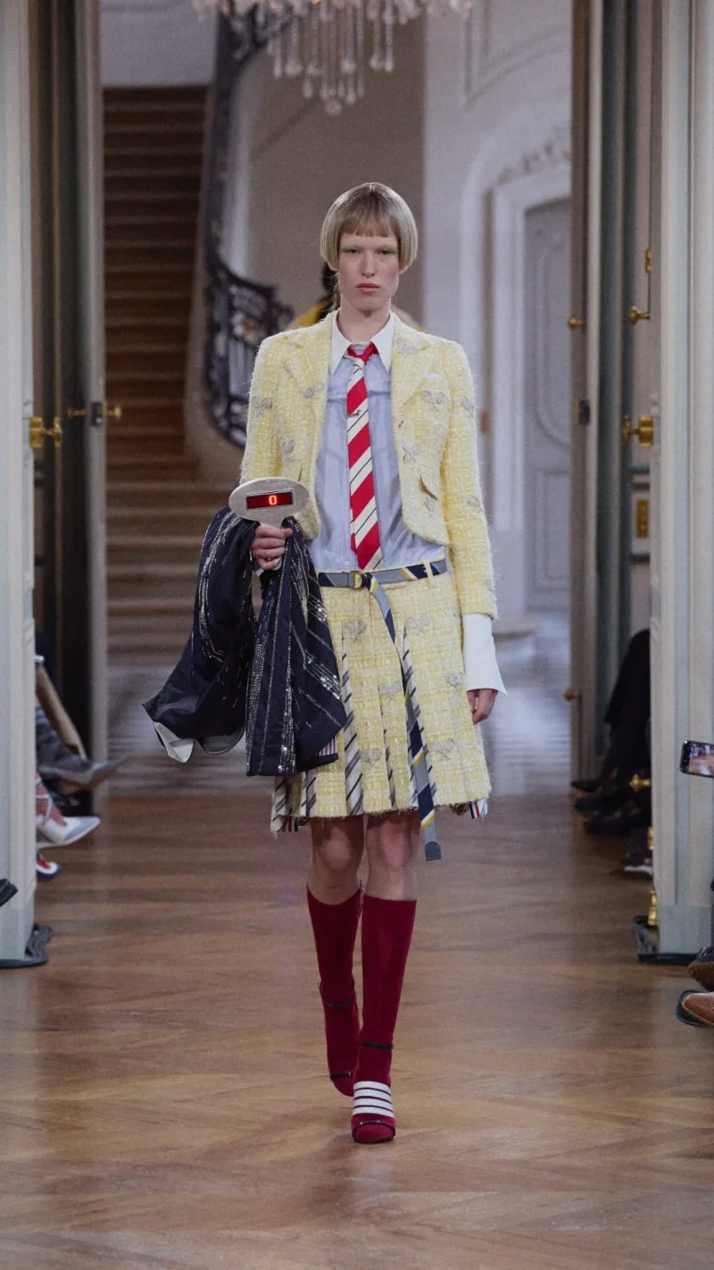 Μοντέλο στην επίδειξη Thom Browne SS26 με κίτρινο ταγιέρ και ριγέ γραβάτα.