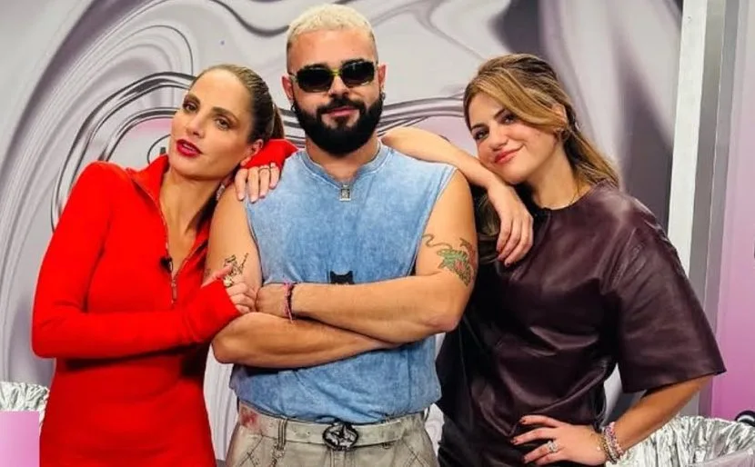 Ο Ακύλας ανάμεσα σε δύο γυναίκες σε τηλεοπτικό πλατό.
