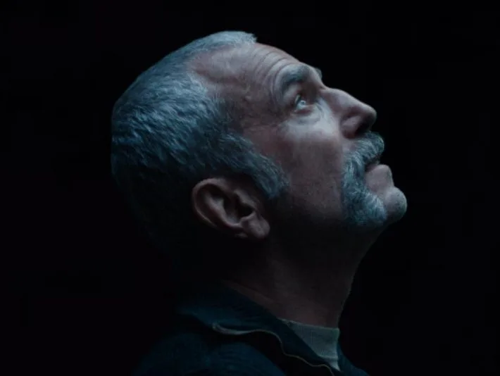 Ο Daniel Day-Lewis σε προφίλ με γκρίζα μαλλιά και μουστάκι, κοιτάζοντας ψηλά.