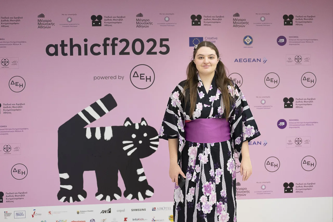 Μια κοπέλα με παραδοσιακό ιαπωνικό ένδυμα yukata μπροστά από το backdrop του athicff2025.