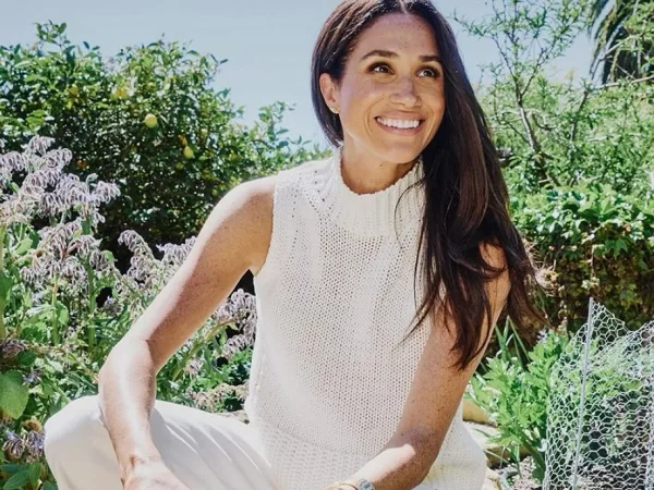 Η Meghan Markle χαμογελάει σε εξωτερικό χώρο, με το άρθρο να αναφέρεται στη συνεργασία της με το Netflix.