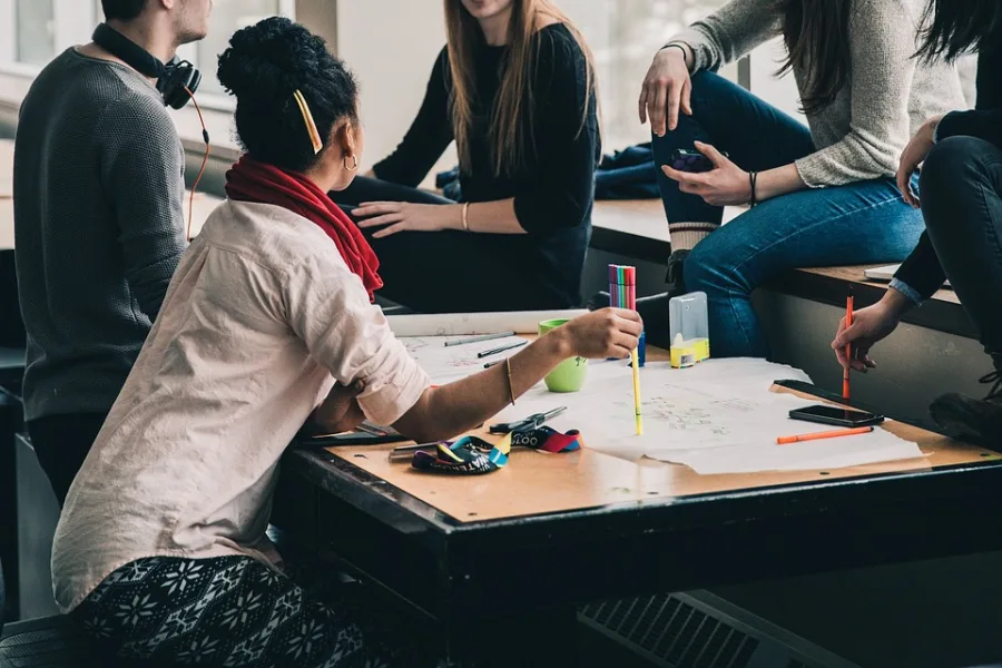 Ομάδα νέων ανθρώπων της Generation Z σε συνεργασία γύρω από ένα τραπέζι.