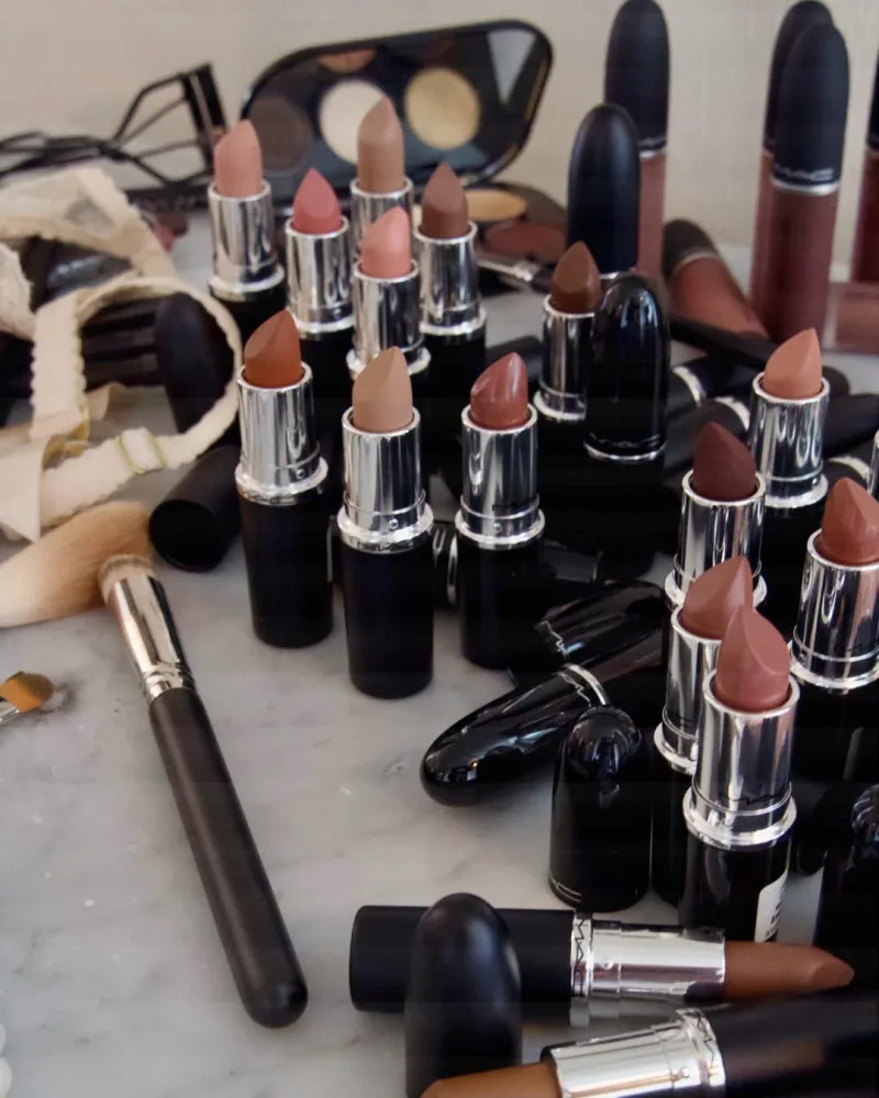 Σειρά από κραγιόν MAC Cosmetics σε διάφορες nude και καφέ αποχρώσεις πάνω σε μαρμάρινη επιφάνεια.