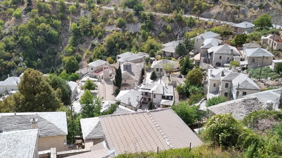 Πανοραμική άποψη παραδοσιακού οικισμού στα Τζουμέρκα με πέτρινα σπίτια και στέγες από σχιστόλιθο.