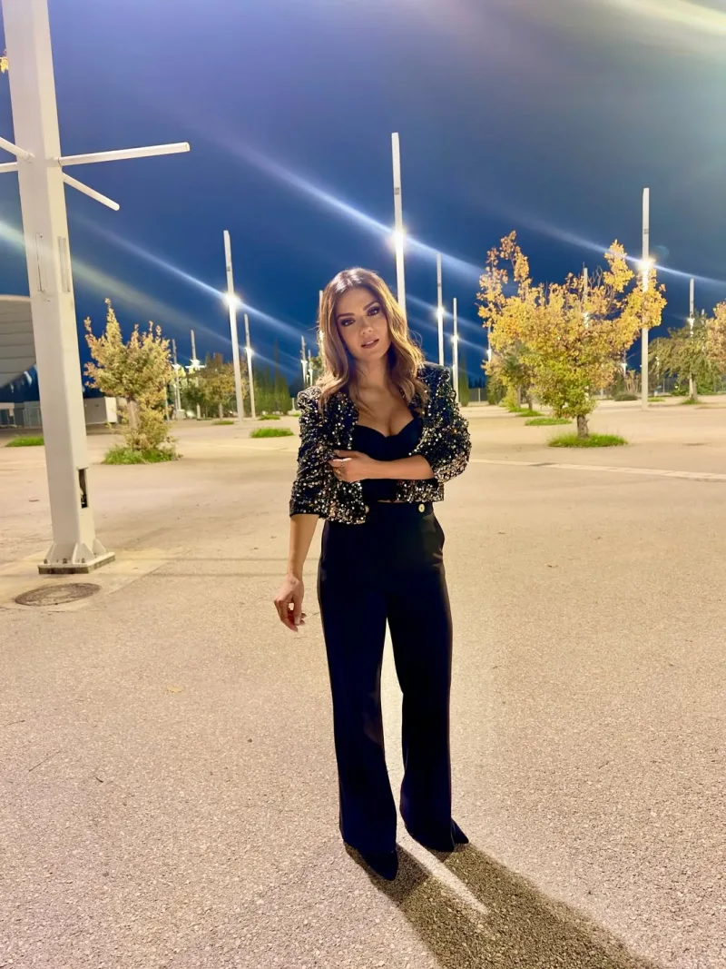 Η Βάσω Λασκαράκη με total black σύνολο και σακάκι με παγιέτες σε εξωτερικό χώρο τη νύχτα.