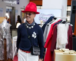 Άνδρας με κόκκινο καπέλο και μπλε πουλόβερ σε εκδήλωση μόδας.