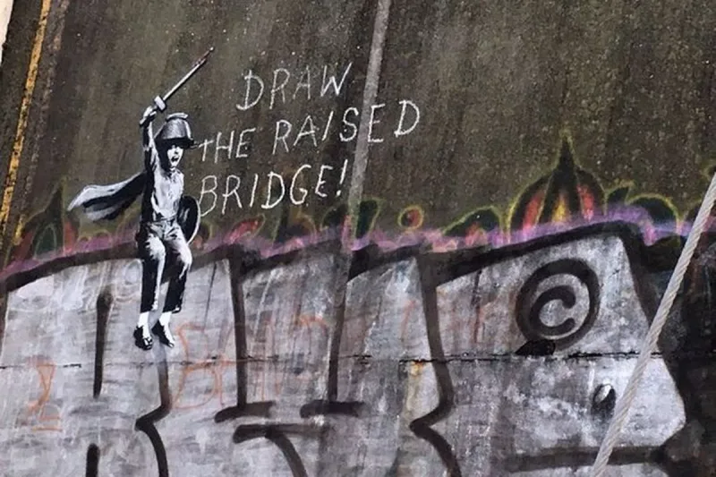 Γκράφιτι του Banksy σε τοίχο με ένα παιδί που κρατά σπαθί και το μήνυμα Draw the raised bridge.