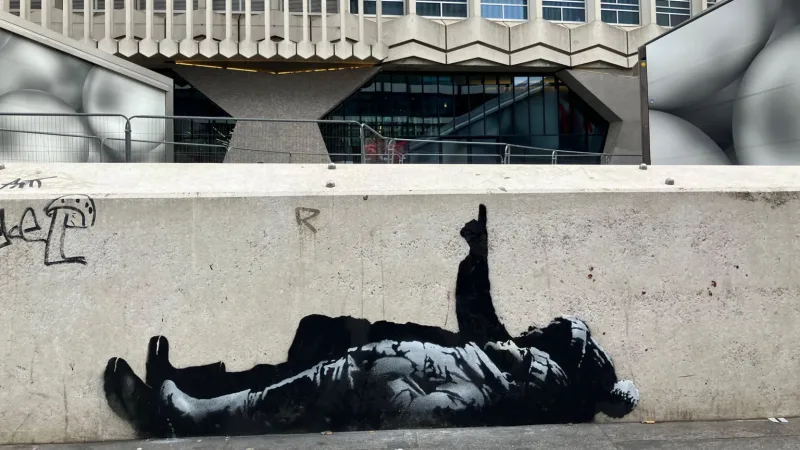 Γκράφιτι του Banksy σε τοίχο στο Λονδίνο που απεικονίζει μια ξαπλωμένη φιγούρα.