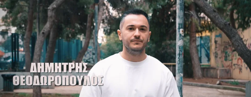 Ο Δημήτρης Θεοδωρόπουλος σε εξωτερικό χώρο με δέντρα.