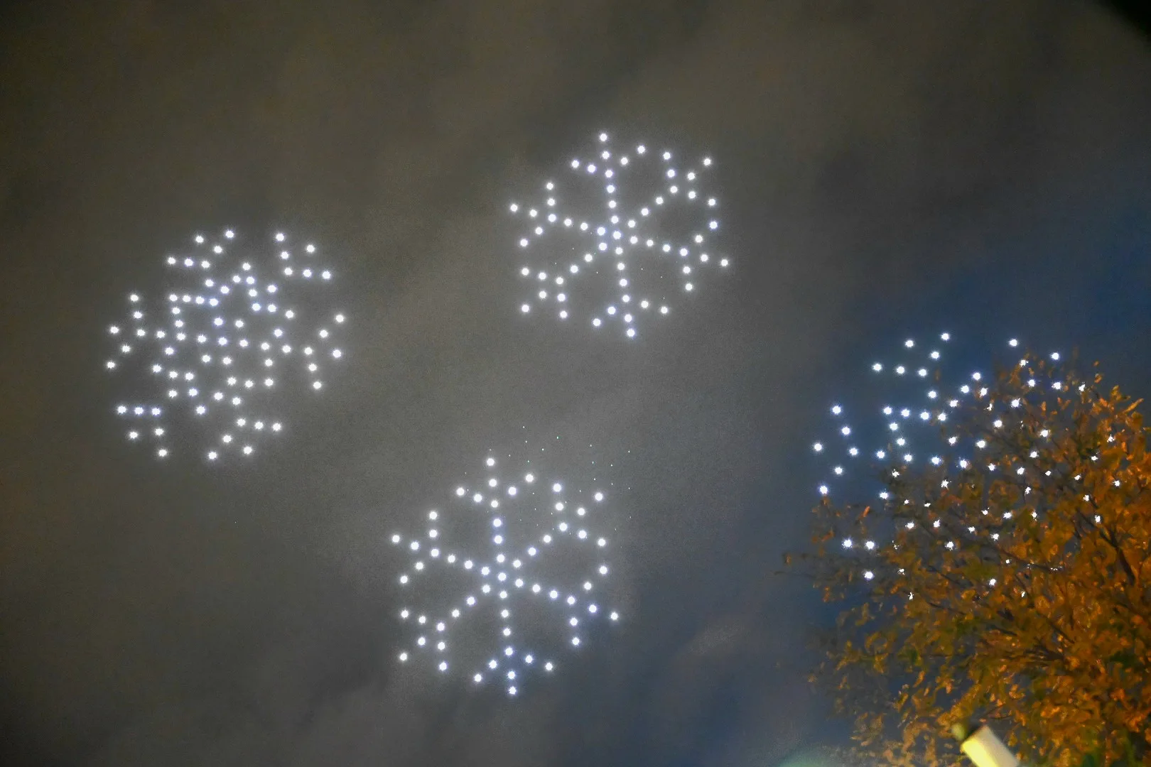 Drone show με φωτεινές νιφάδες χιονιού στον νυχτερινό ουρανό.