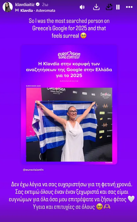Η Κλαυδία κρατά την ελληνική σημαία μπροστά από το λογότυπο της Eurovision.