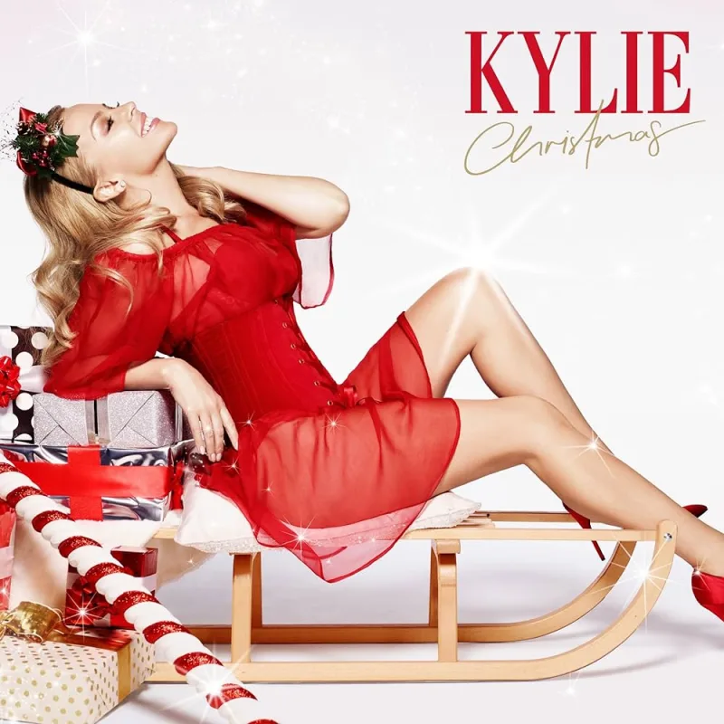 Η Kylie Minogue με κόκκινο φόρεμα σε ξύλινο έλκηθρο για το άλμπουμ Kylie Christmas.