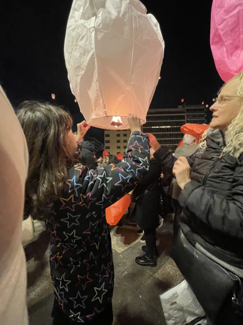 Ένα παιδί και μια γυναίκα κρατούν ένα λευκό φαναράκι στην πλατεία Κοτζιά κατά τη Νύχτα των Ευχών.