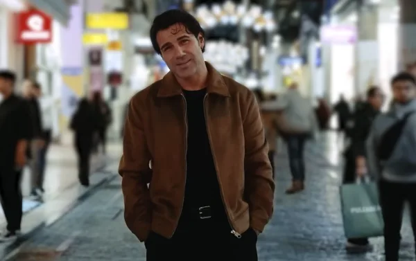 Ο Πέτρος Ιακωβίδης σε εξωτερικό χώρο με καφέ τζάκετ.