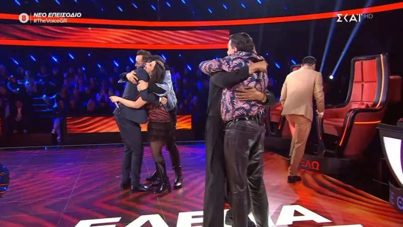 Στιγμιότυπο από τα battles του The Voice of Greece με διαγωνιζόμενους και coaches να αγκαλιάζονται στη σκηνή.