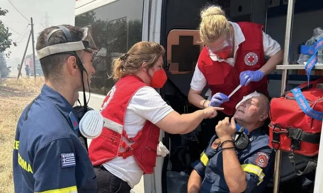 Εθελοντές του Ελληνικού Ερυθρού Σταυρού προσφέρουν πρώτες βοήθειες σε πυροσβέστη.