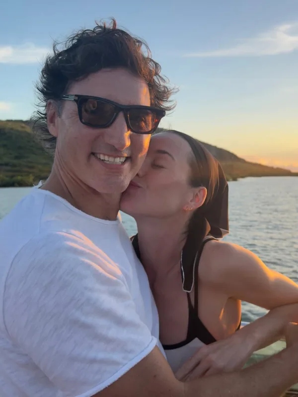 Η Katy Perry φιλά τον Justin Trudeau στο μάγουλο με φόντο το ηλιοβασίλεμα.