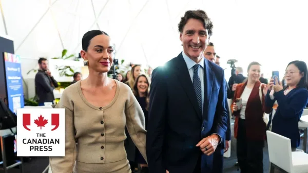 Η Katy Perry και ο Justin Trudeau περπατούν χαμογελαστοί σε εσωτερικό χώρο εκδήλωσης.